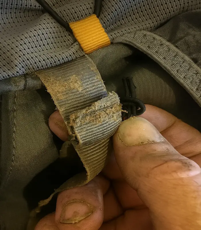 A broken, brittle PP webbing strap contrasted with a strong, intact nylon webbing strap on a backpack.