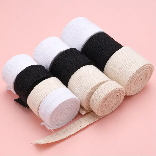 A collection of natural-colored cotton webbing rolls, highlighting their soft texture.