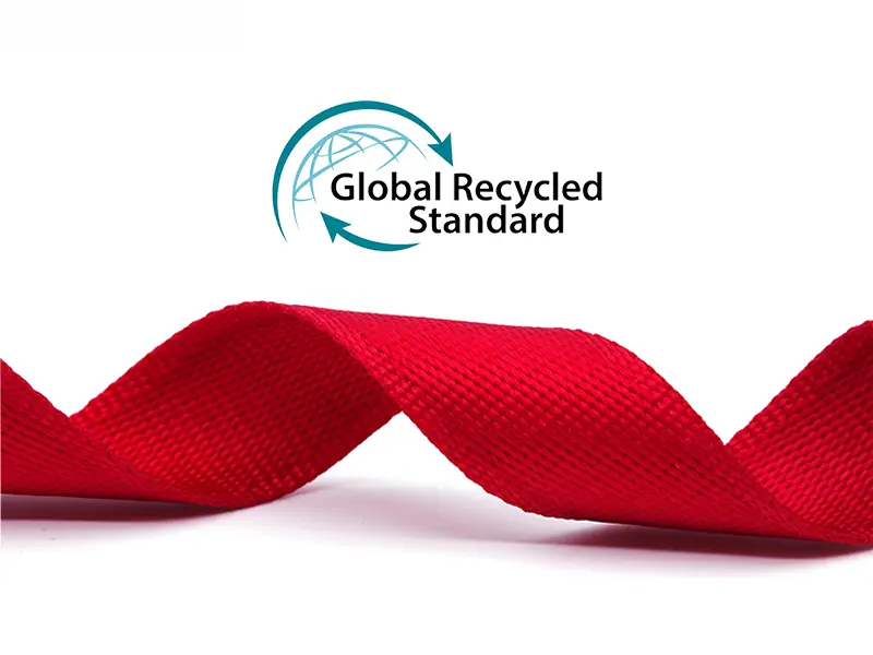 Rolls of eco-friendly rPET webbing next to recycled plastic flakes, illustrating the recycling process.