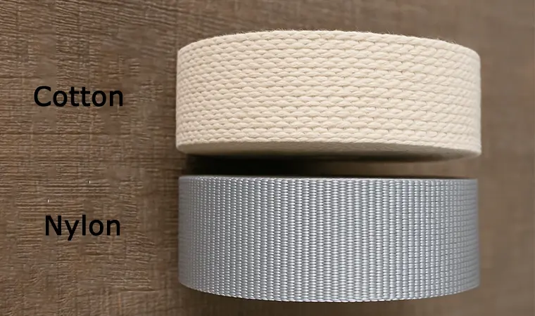 A side-by-side comparison showing the soft, matte texture of natural cotton webbing next to the smooth, slightly shiny synthetic nylon and polyester webbing rolls.