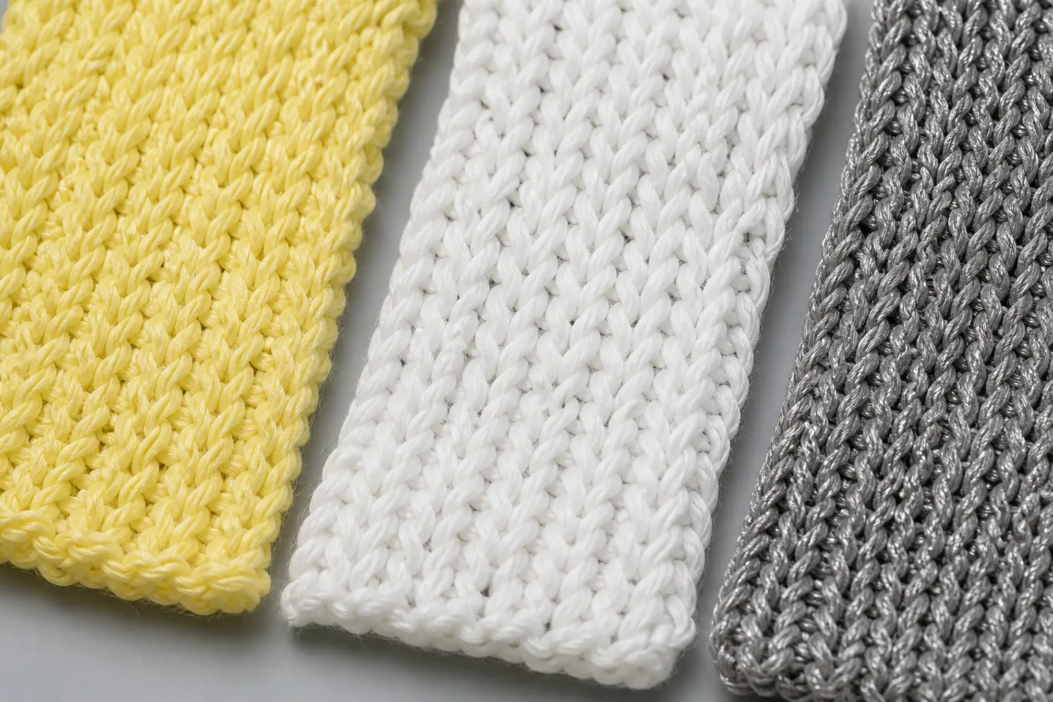 Close-up of cut resistant glove webbing samples showing aramid (Kevlar), HPPE, and steel-core composite yarn knit construction in yellow, white, and grey colors.